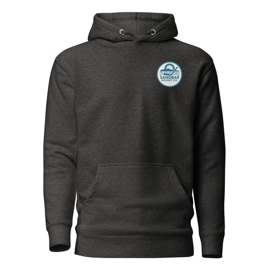 Black hockey hoodie front side with small circular Sandbar Hockey Co. chest logo featuring sunset, water, and hockey stick