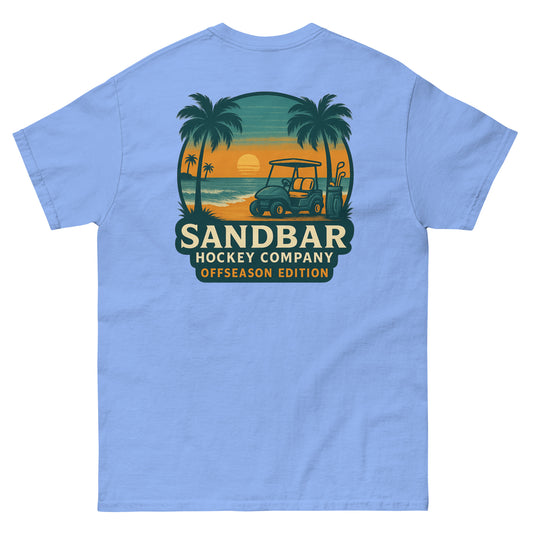 Carolina blue T-shirt with a large back graphic of a beach sunset scene featuring palm trees, ocean waves, a golf cart, hockey sticks, and the text “Sandbar Hockey Company Offseason Edition.”