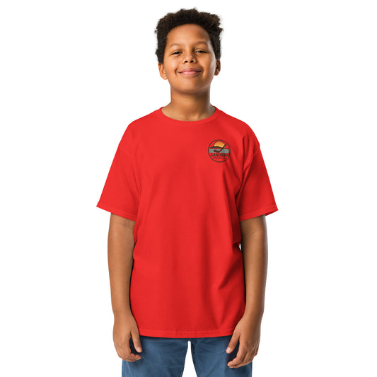 Red youth hockey t-shirt front side on model with small circular Sandbar Hockey Co. sunset, water, island, and hockey stick chest logo