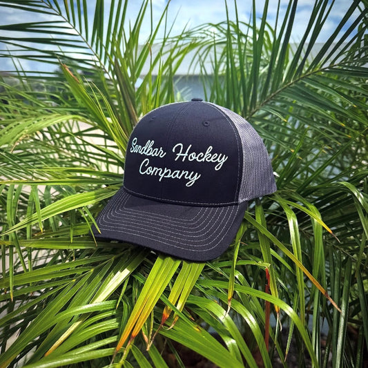 Sandbar Hockey Company black trucker hat outdoors with embroidered hockey logo