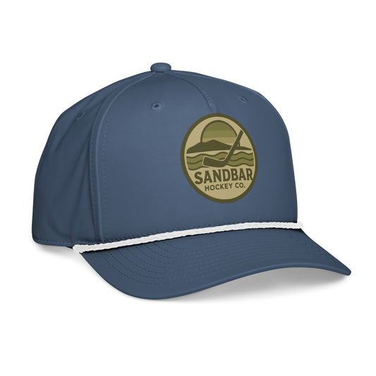 Blue hockey rope hat left front angle view with olive Sandbar Hockey Co. sunset logo, white rope detail, and curved brim.