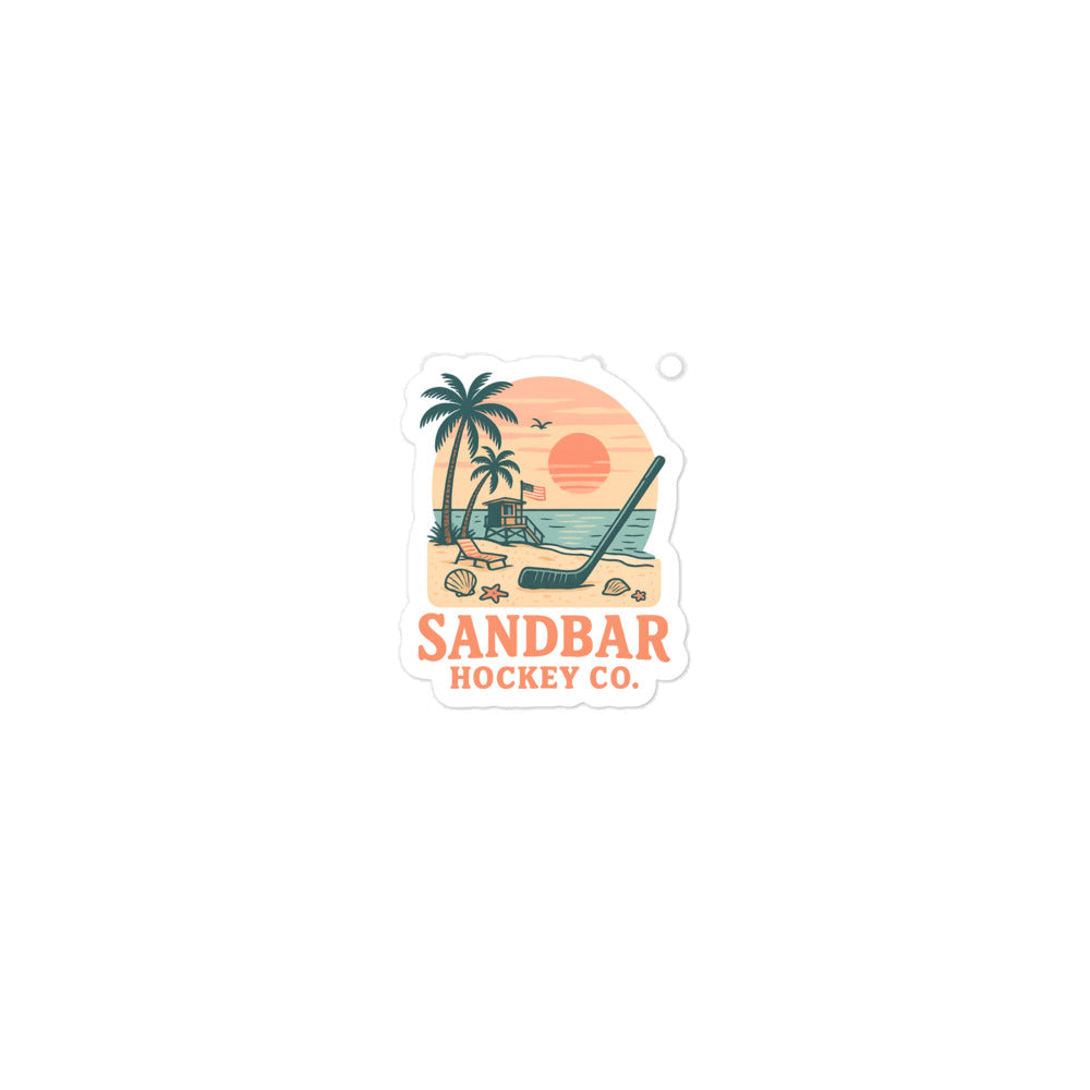 Small Sandbar Hockey Co. sticker with palm trees, beach sunset, lifeguard stand, seashells, ocean water, and a hockey stick in the sand.