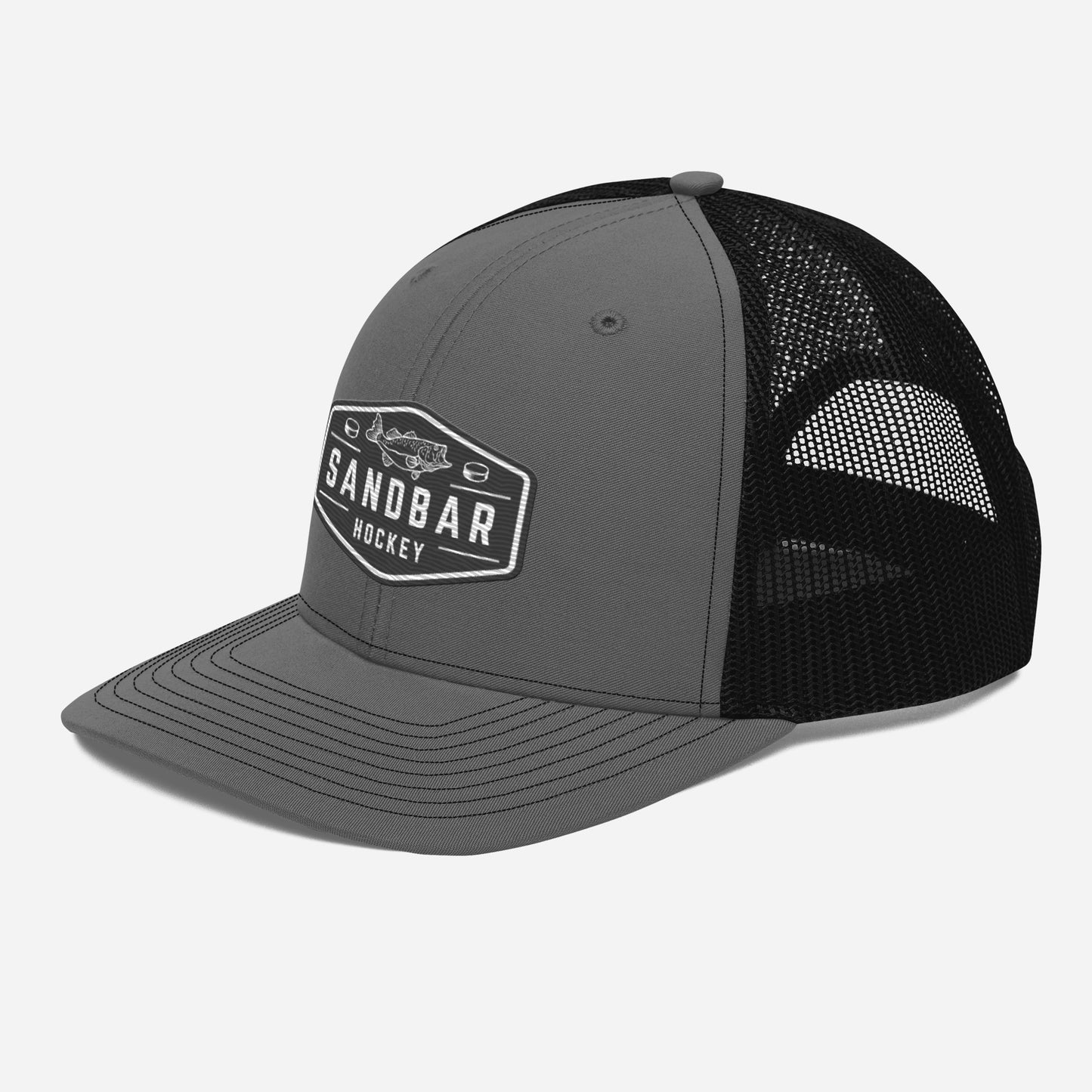 Dark grey and black Sandbar Hockey snapback hat left side angle view with rectangular fish badge logo and curved brim