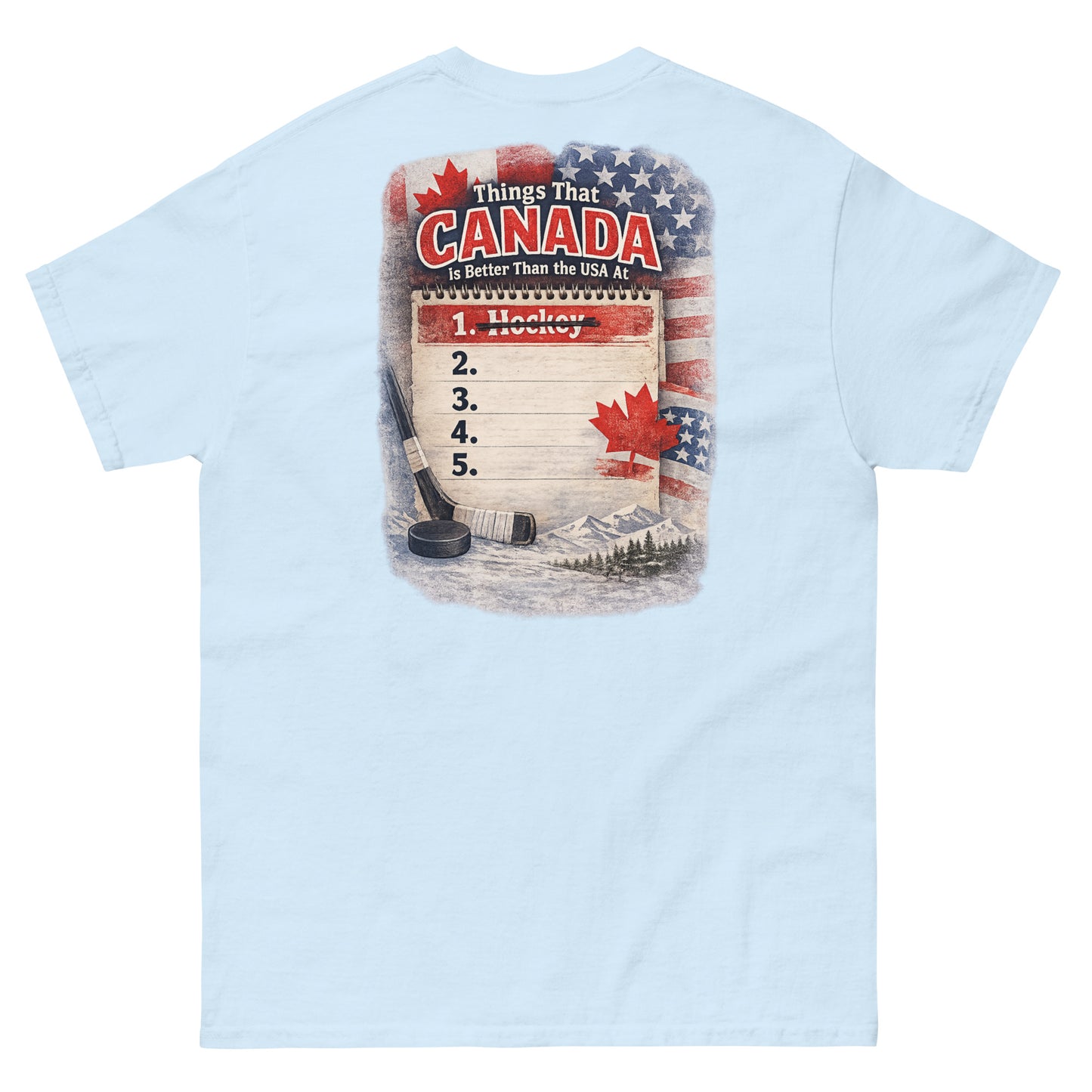 Light blue hockey t-shirt with large back graphic that reads “Things That Canada Is Better Than the USA At” with “Hockey” crossed out at number one, plus American and Canadian flag elements, a hockey stick, puck, and mountain background.