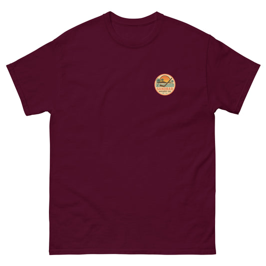 Maroon hockey t-shirt front side with small circular Sandbar Hockey Co. sunset, palm tree, ocean wave, and hockey stick chest logo