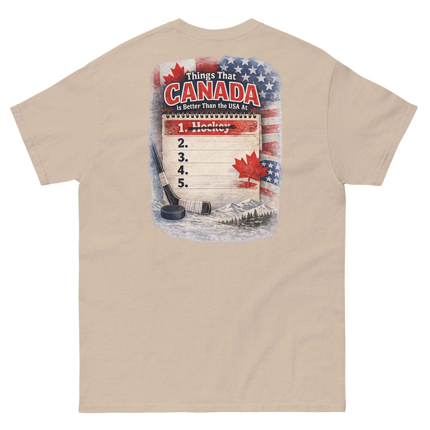 Sand-colored hockey t-shirt with large back graphic that reads “Things That Canada Is Better Than the USA At” with “Hockey” crossed out at number one, plus American and Canadian flag elements, a hockey stick, puck, and mountain background.