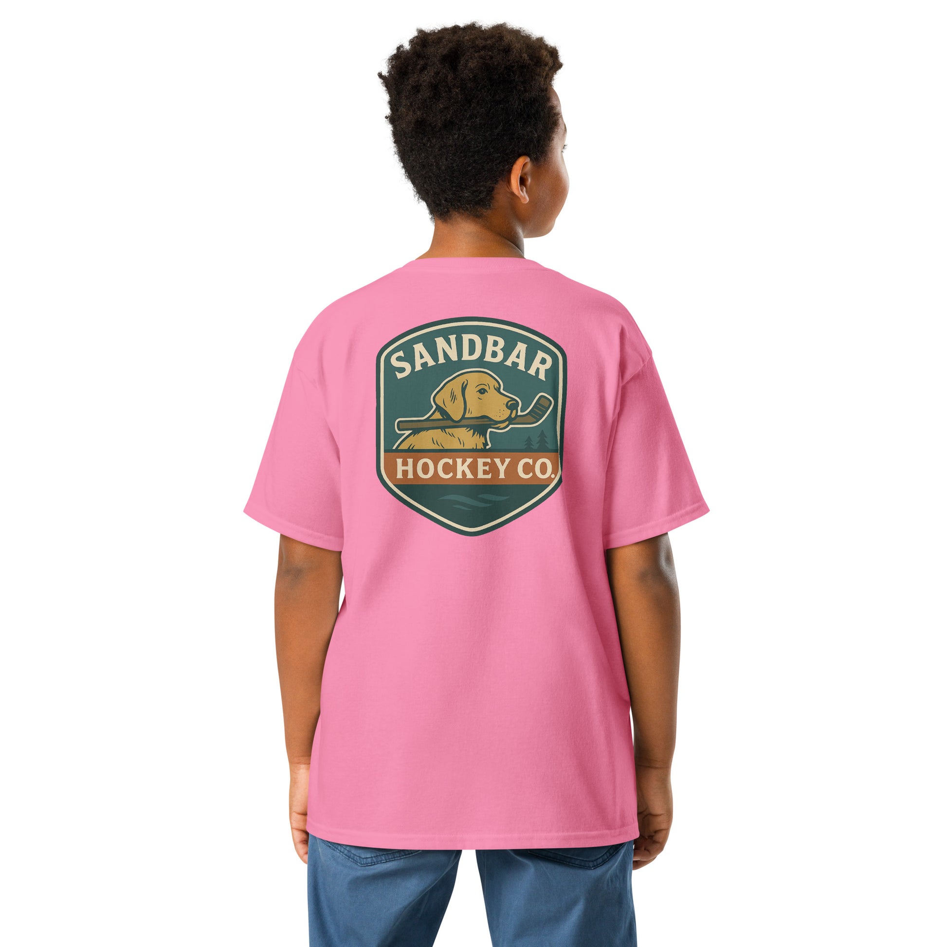 Youth pink Sandbar Hockey Dog Badge T-Shirt back view on model with large badge graphic of a dog holding a hockey stick in its mouth