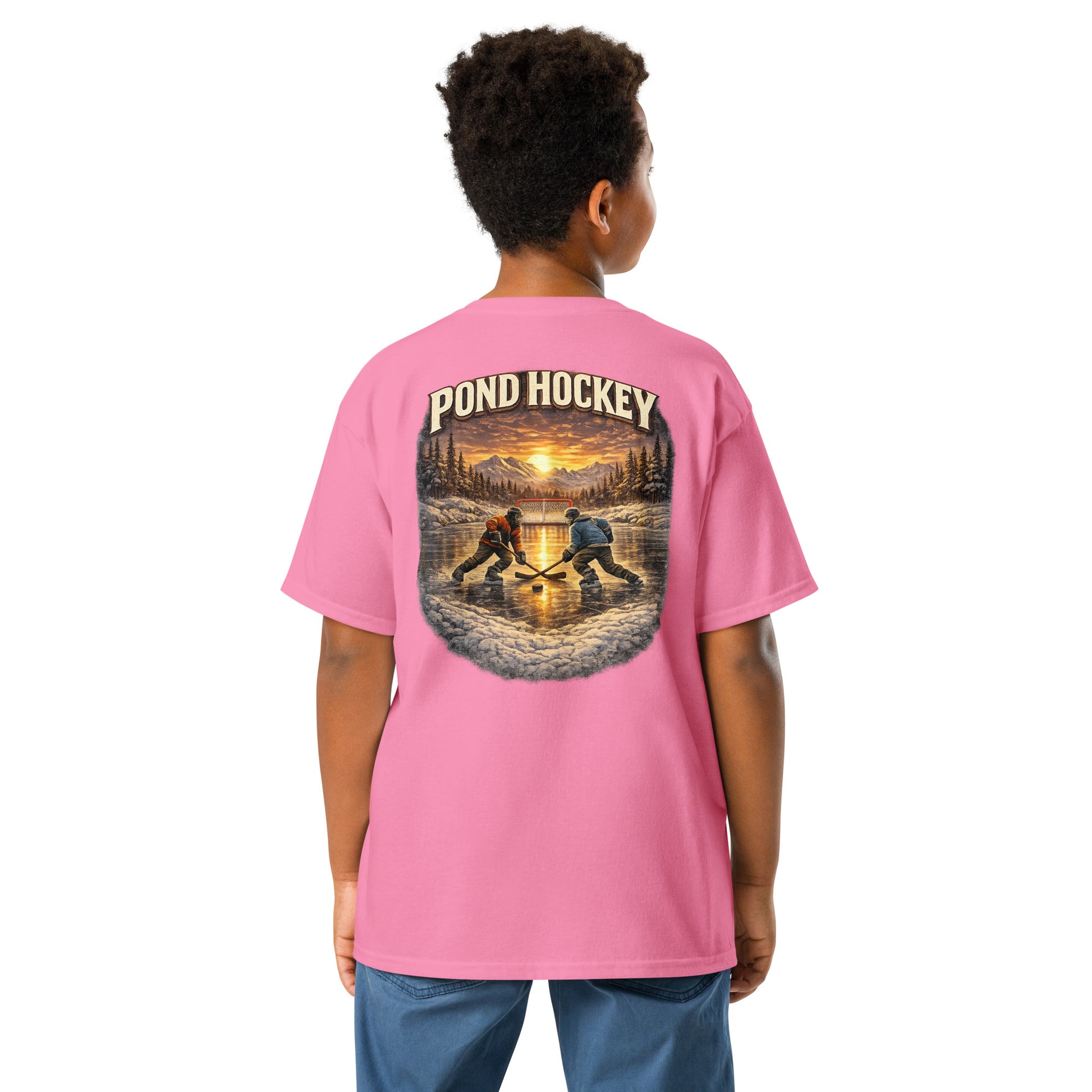 Pink youth T-shirt with a large back graphic showing two hockey players on a frozen pond at sunset, with mountains, pine trees, a goal net, and “POND HOCKEY” in bold lettering above.