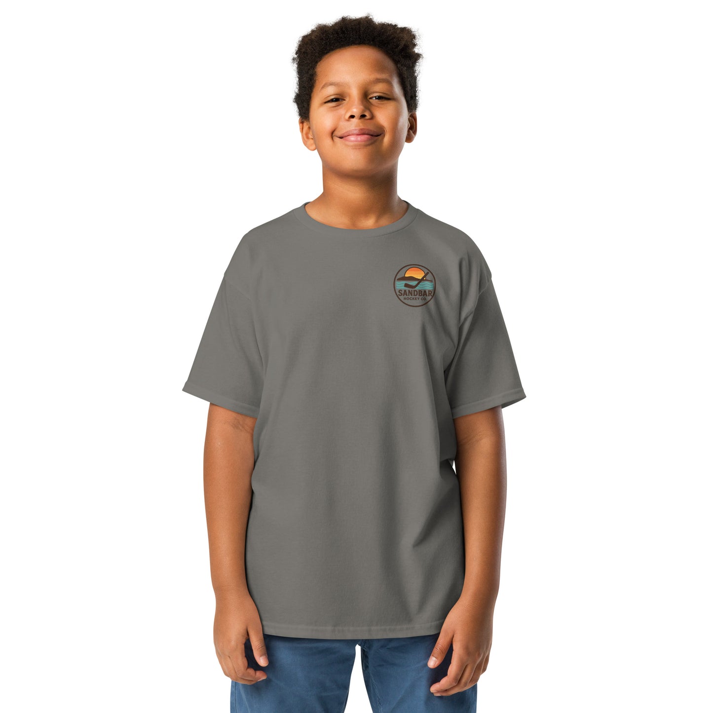 Charcoal youth hockey t-shirt front side on model with small circular Sandbar Hockey Co. sunset, water, island, and hockey stick chest logo