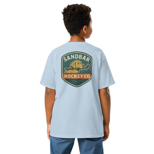 Youth light blue Sandbar Hockey Dog Badge T-Shirt back view on model with large badge graphic of a dog holding a hockey stick in its mouth