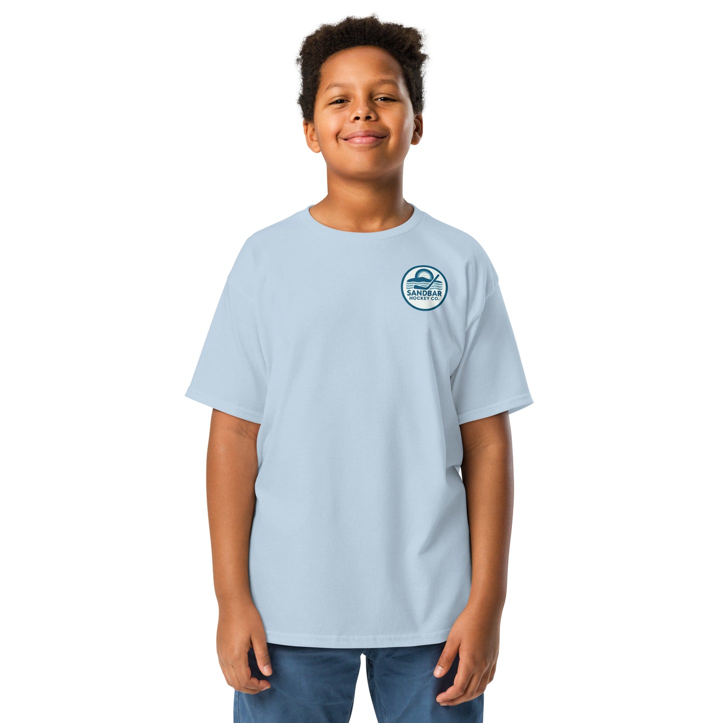 Light blue youth hockey t-shirt front side on model with small circular Sandbar Hockey Co. sunset, water, and hockey stick chest logo