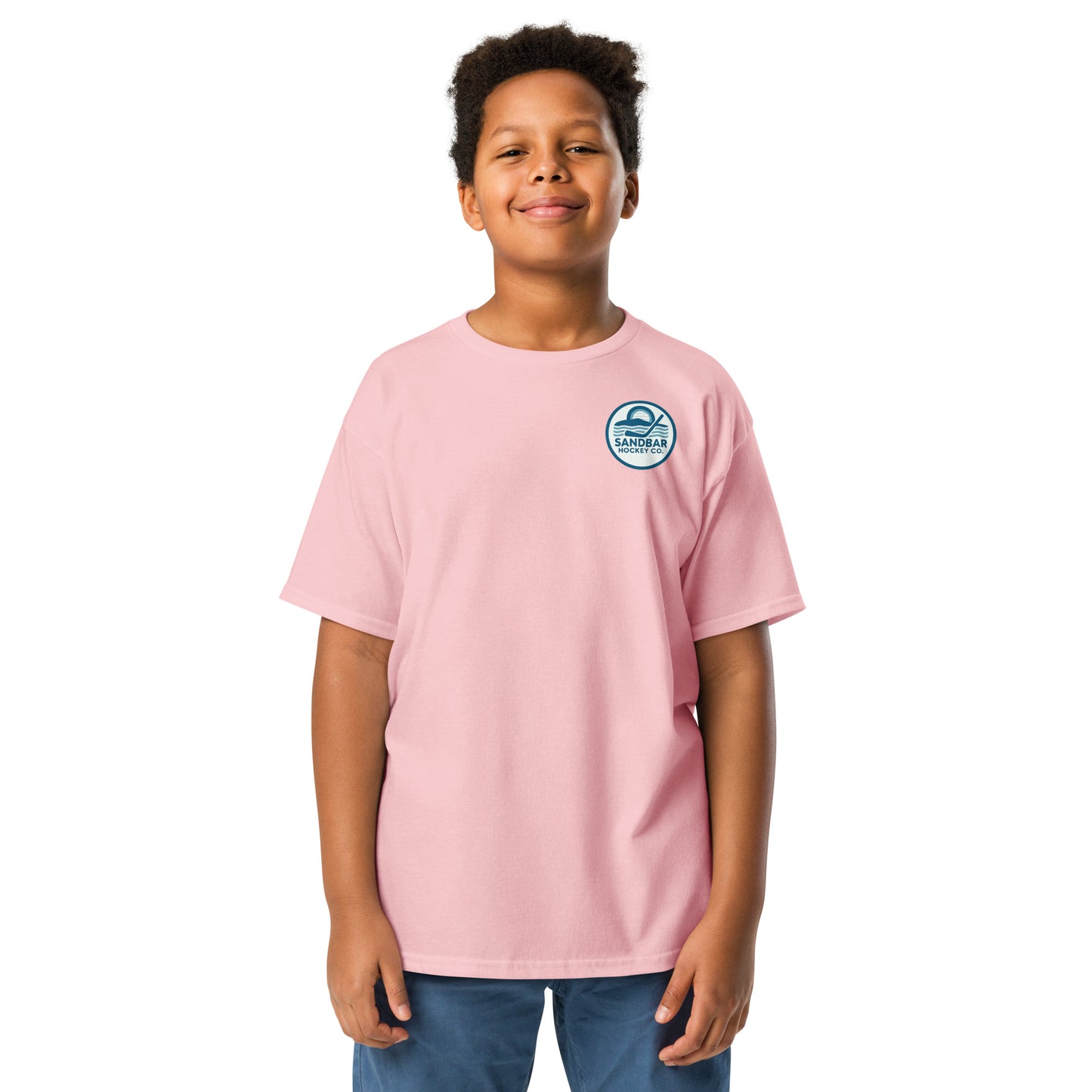 Light pink youth hockey t-shirt front side on model with small circular Sandbar Hockey Co. sunset, water, and hockey stick chest logo