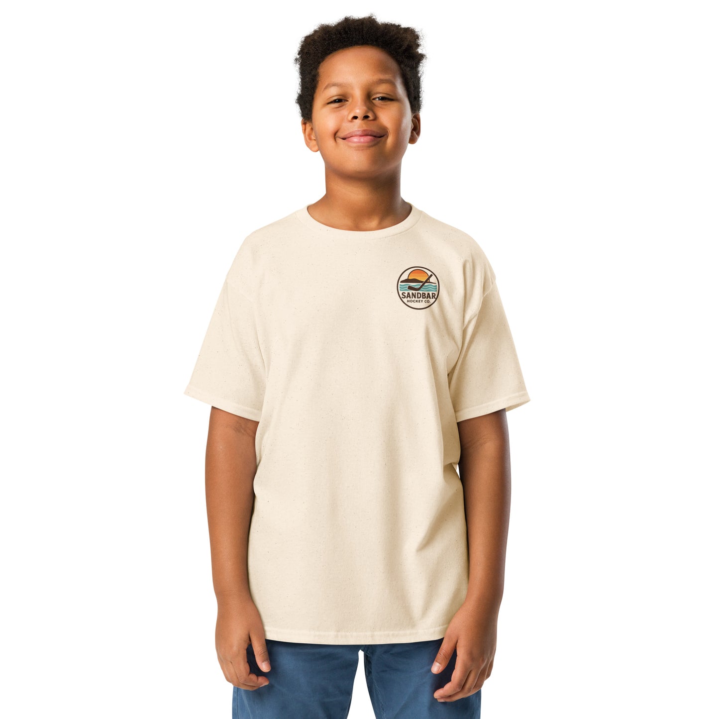 Natural youth hockey t-shirt front side on model with small circular Sandbar Hockey Co. sunset, water, island, and hockey stick chest logo