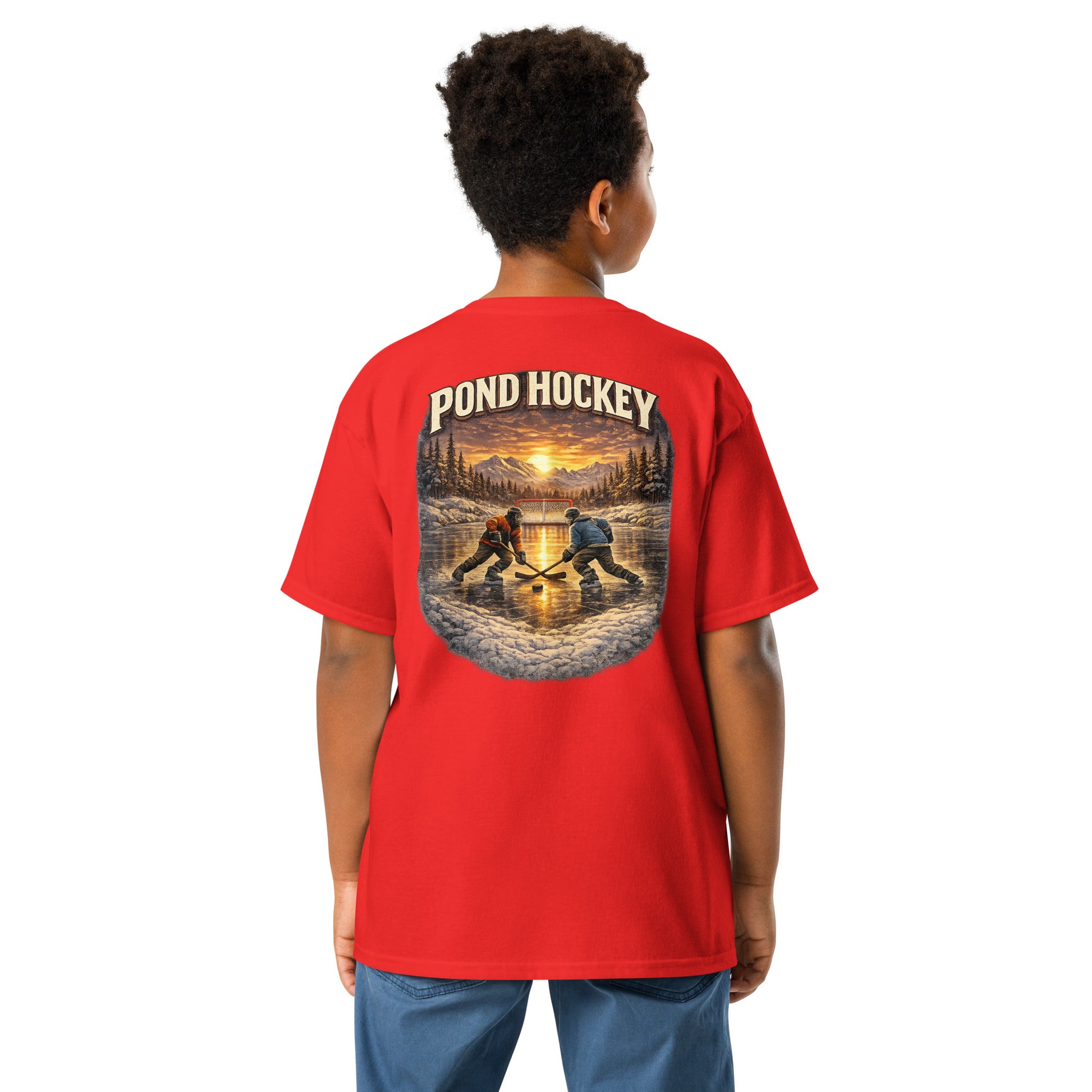 Red youth T-shirt with a large back graphic showing two hockey players on a frozen pond at sunset, with mountains, pine trees, a goal net, and “POND HOCKEY” in bold lettering above.