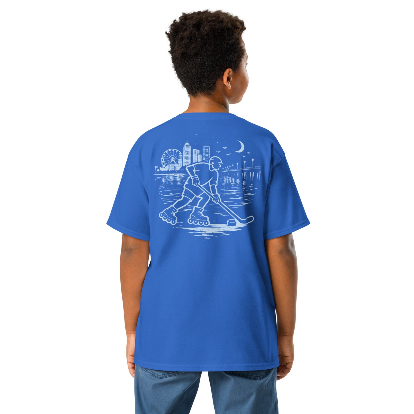 Youth royal blue roller hockey t-shirt back view worn by a boy with baby blue waterfront roller hockey graphic featuring a skater, city skyline, ferris wheel, pier, moon, and water reflections.