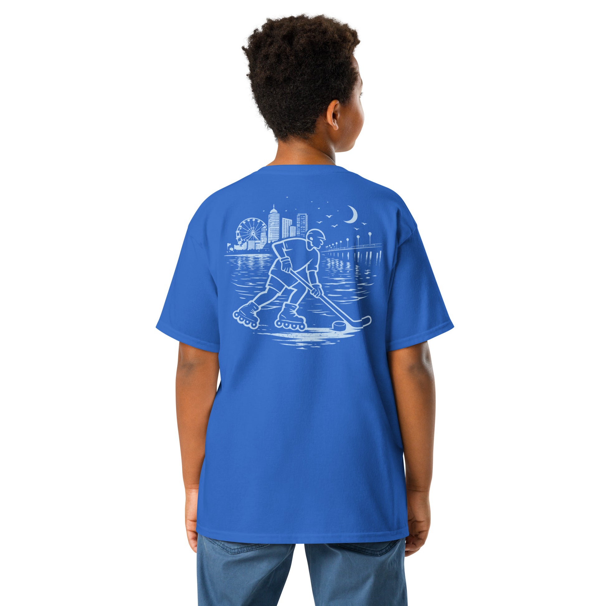Youth royal blue roller hockey t-shirt back view worn by a boy with baby blue waterfront roller hockey graphic featuring a skater, city skyline, ferris wheel, pier, moon, and water reflections.